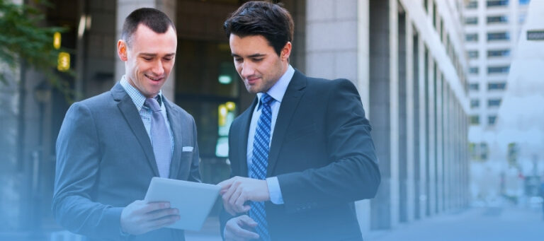 Hombre trajeados revisando comunicado en línea en una tablet